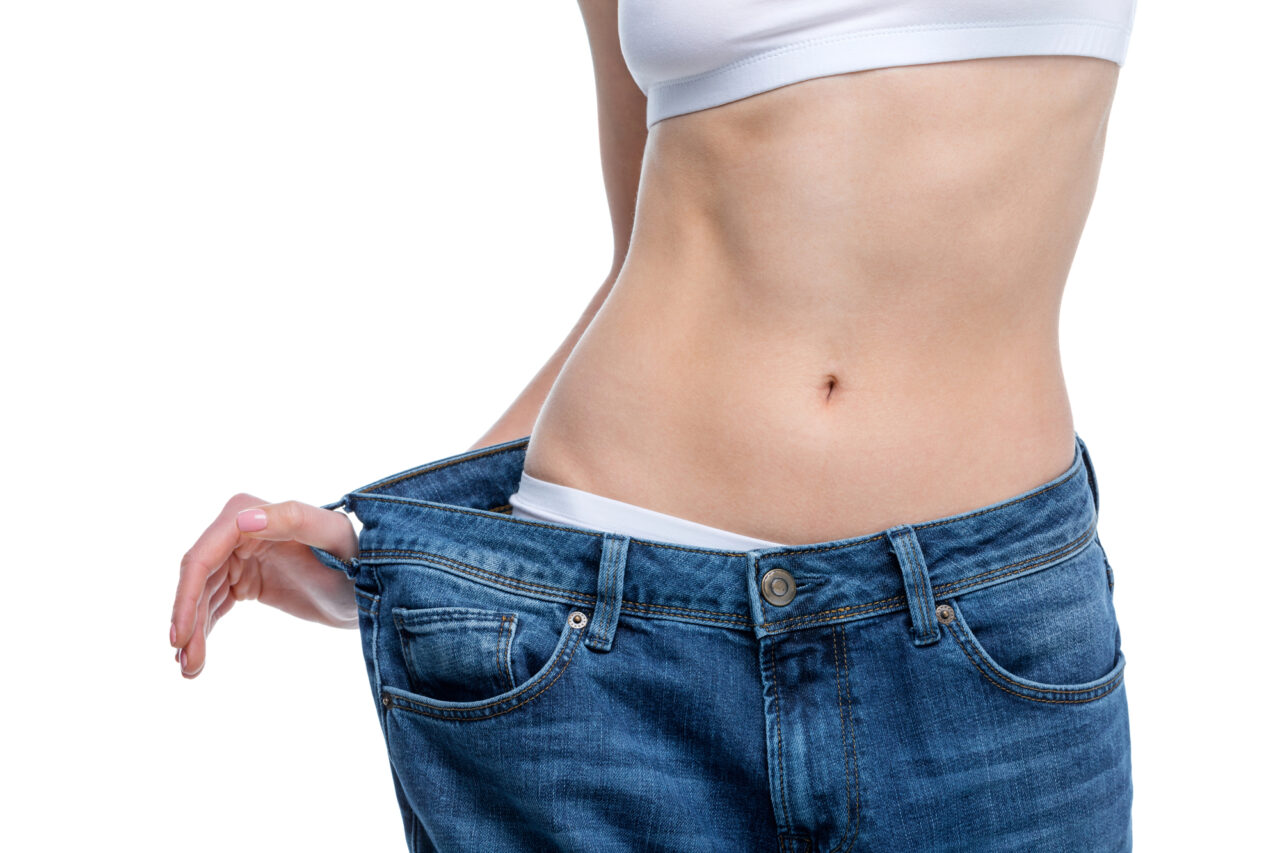 slim woman holding out waist of large pants