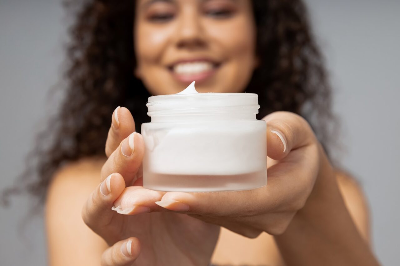 woman holding out jar of face cream