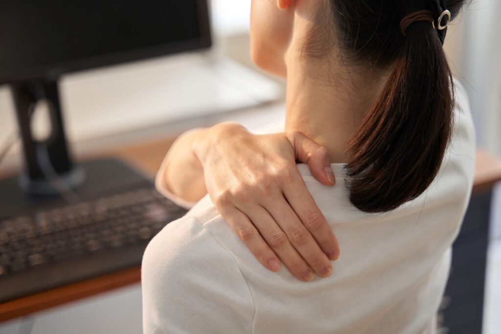 woman with hand on shoulder sitting at desk
